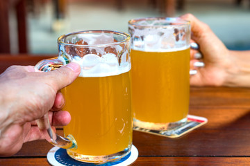 Male and female hands clink mugs with beer
