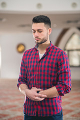 Young Muslim standing in prayer with hands on belly