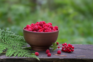 ripe raspberries in a bowl on old wooden table with a blurred background
