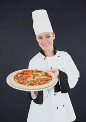 Chef with pizza against black background