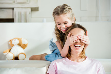 Happy mother and daughter having fun and playing at home