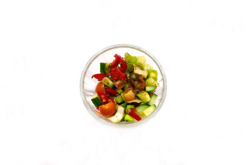 Salad of fresh vegetables cherry tomatoes cucumber tasty in a transparent bowl top view and on a white background