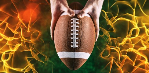 Composite image of american football player holding up football