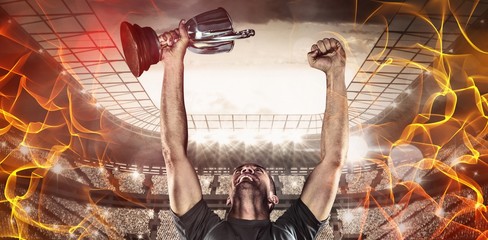 Composite image of happy rugby player holding trophy - Powered by Adobe