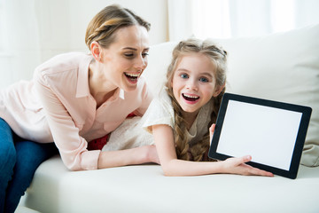 portrait of excited mother and daughter showing digital tablet