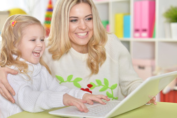 mother with little daughter using laptop