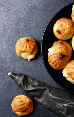 Profiteroles eclairs on black matte plate .Top view .Copy space