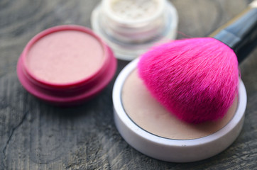 Pink makeup brush,compact powder and blush on old wooden background with copy space.Fashion cosmetic make-up or woman beauty accessories concept.Selective soft focus.