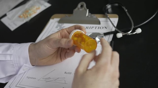 Doctor filling a medical prescription on his note pad.