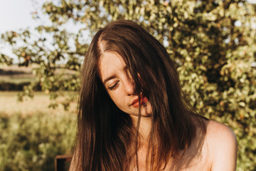 Fototapeta premium sensual woman relaxing in evening under sunlight in summer field. stylish hipster girl traveling. tender sensual portrait in sunshine.