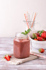 Strawberry smoothie or milkshake in jar on white wooden rustic background