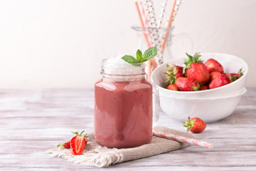 Strawberry smoothie or milkshake in jar on white wooden rustic background