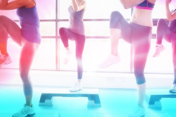 Composite image of women raising their legs while doing aerobics