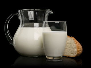 Piece of a white loaf and glassware filled with milk