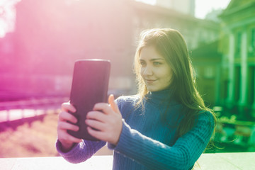 Smiling young woman taking selfie on street