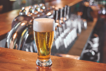 Beer glass on a bar table. Beer Tap on background