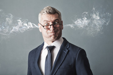 Closeup portrait of angry businessman, blowing steam coming out of ears