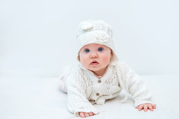 Cute baby in white knitted hat and sweater on a white background.