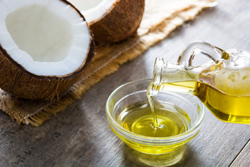 Pouring coconut oil in a bowl on wooden background