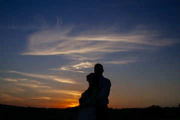 Fototapeta na wymiar Silhouettes of a loving couple hugging at sunset