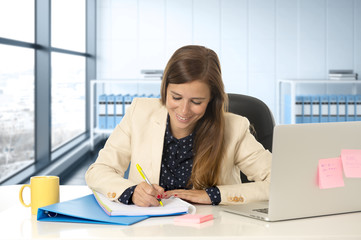 woman on her 30s at office working at laptop computer desk taking notes