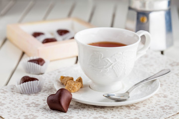 Obraz na płótnie Canvas tea in a white cup with chocolate candies