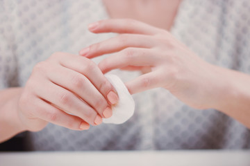 Woman is cleaning nail polish with the cotton pad