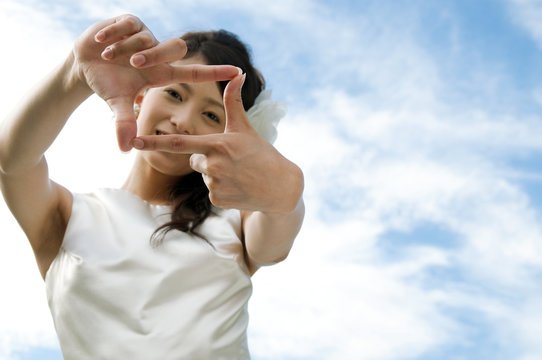 Young woman wearing a wedding dress making frame with hands