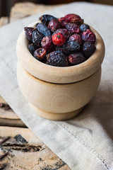 Dried rose hip berries in wood bowl, on linen towel, health concept, natural medicine, closeup
