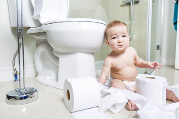 Toddler ripping up toilet paper in bathroom