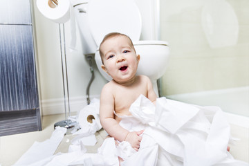 Toddler ripping up toilet paper in bathroom