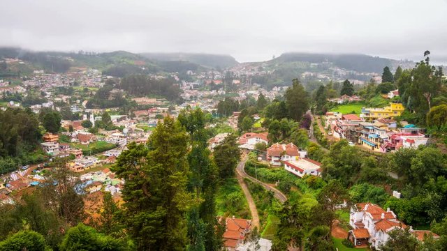 Nilgiri mountains in Ooty, South India. View of the picturesque valley during the cloudy day. Beautiful houses and hotels. Very green touristic area. Time-lapse during the rain