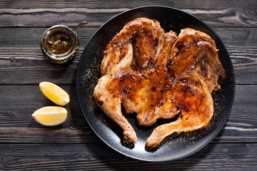Grilled Roasted сhicken tabaka and hot tomato sauce on a wooden background