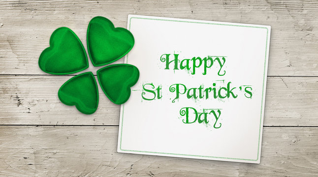 Happy St Patrick's Day greeting card and clover over wood