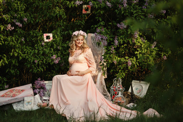 Obraz na płótnie Canvas Young woman with pregnant belly in spring lilac garden. Pregnant girl
