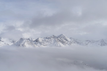 Mit Schnee bedeckte Alpengipfel in weißen Wolken