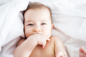 baby girl lying on white sheet