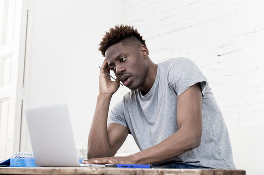african american man sitting at home living room working with laptop computer and paperwork