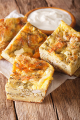 Serbian pie Gibanitsa with cheese, eggs and herbs close-up and yogurt. vertical