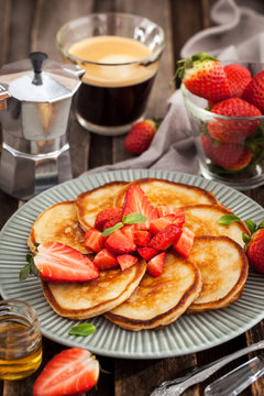 Homemade delicious pancakes served with fresh strawberries and honey
