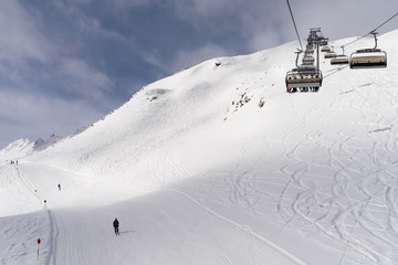 Sessellift an einem verschneiten Berghang mit blauem Himmel