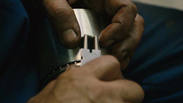 Car Mechanic Putting a Small Metal Rim into a Piston