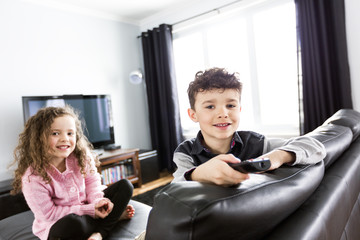 Two young children in living room with flat screen