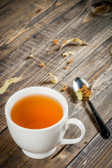 The concept of home spring relaxation: herbal homemade linden tea and an old book for reading, copy space