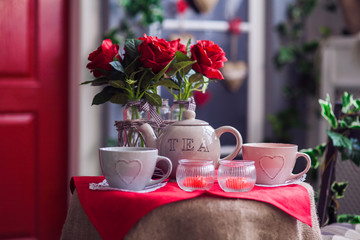 Porch with red door and climbing ivy on the wall. Wicker rocking chair at the spring terrace. Front view