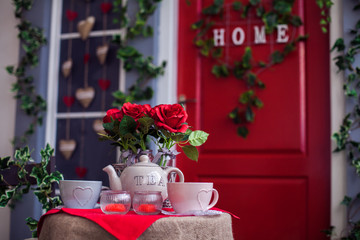 Porch with red door and climbing ivy on the wall. Wicker rocking chair at the spring terrace. Front view