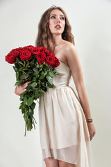 Portrait of a beautiful fashionable girl in the studio with a bouquet of roses