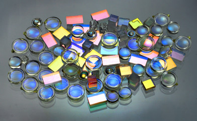Small plastic lenses semitransparent mirrors and prisms on glass. Parts of scientific optical ...