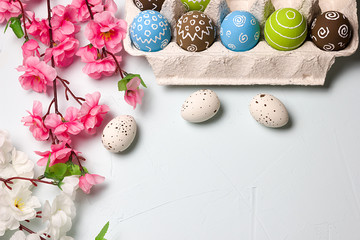 Obraz na płótnie Canvas Painted easter eggs and branches of spring sakura closeup on a light blue background with space for congratulation