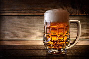 Mug of beer on rustic wooden background with copy space.